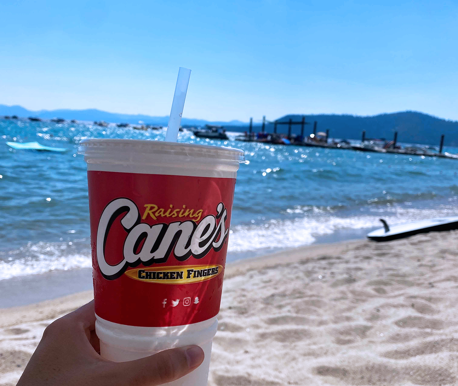 Raising Cane's beverage being enjoyed on the beach