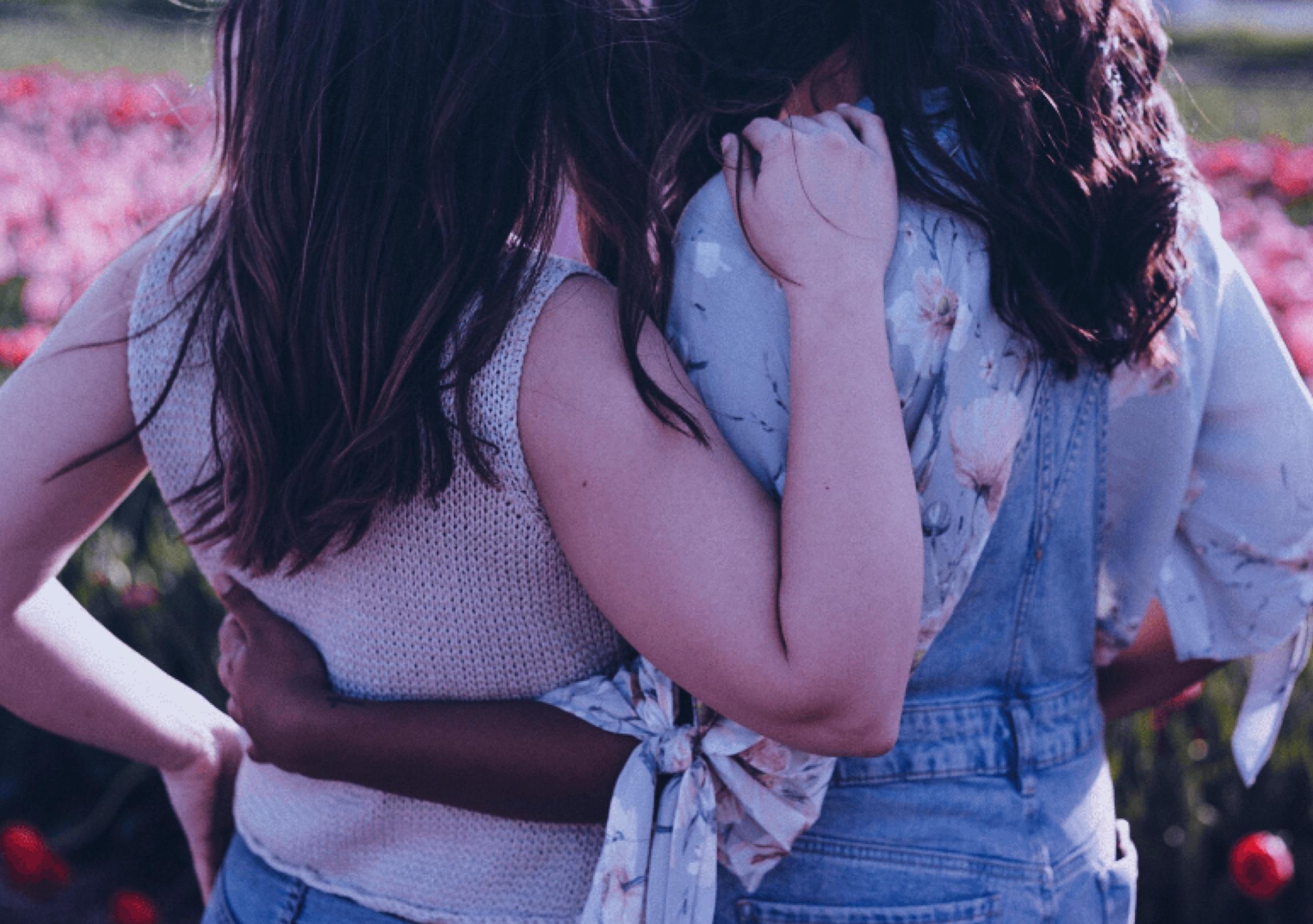 Two man standing with their backs to the camera embracing