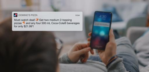 screengrab of Domino's Canada tweet overlaid on an image of a girl holding her phone looking at the Domino's Twitter